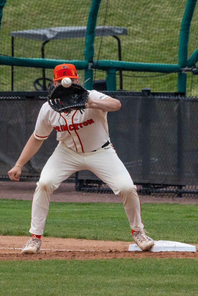 First baseman Nick Shenefelt, his face obscure by his mitt, is just about to squeeze the ball for an out.
