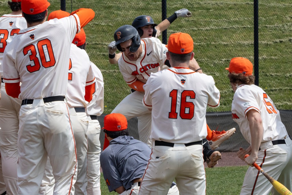 Princeton's Jake Bold, surrounded by teammates near home plate, leaps into the air to celebrate a home run.