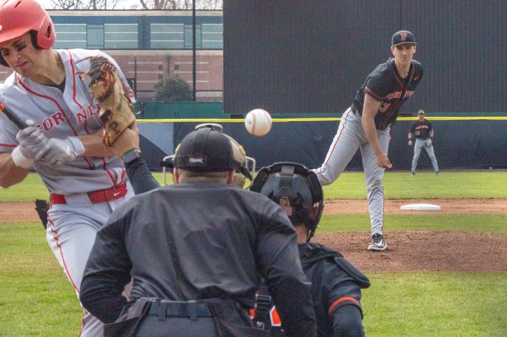 A Cornell batter turns away and winces after a pitch conked him on the shoulder. The ball ricochets away.