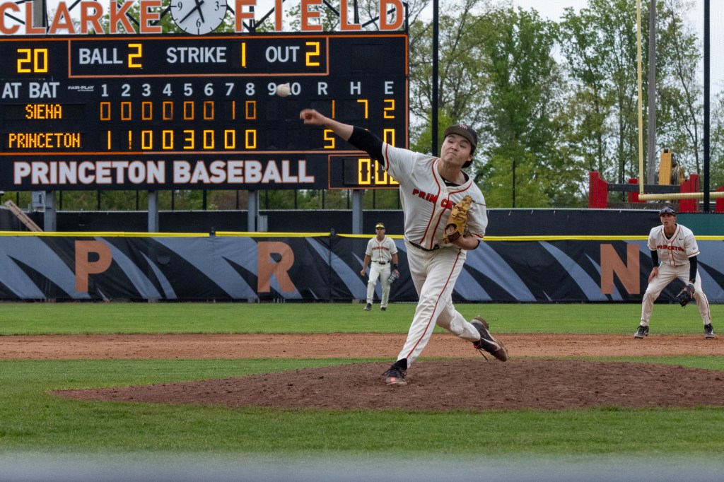 Princeton pitcher Ethan Hsu delivers a pitch to the plate, with the scoreboard behind him showing the Tigers leading 5-1 in the ninth inning.