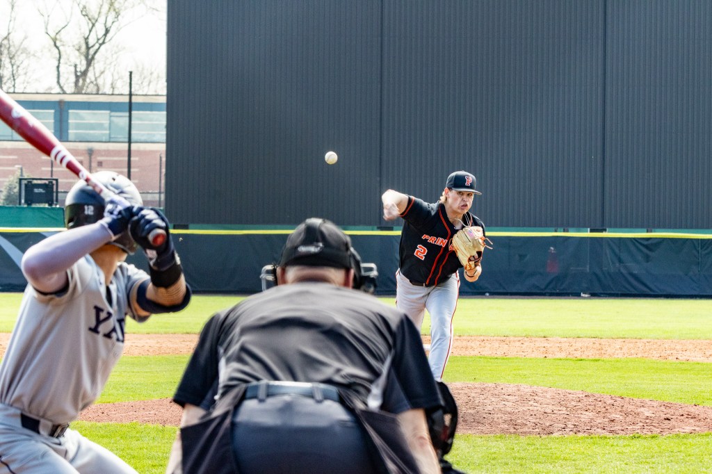 The ball leaves the pitcher's hand on the way to the right-handed batter preparing to swing at home plate. The crouching umpire tracks the ball.
