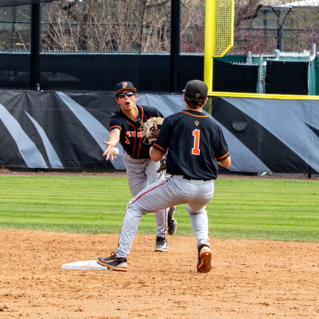 Princeton shortstop tosses the ball underhand to the second baseman stepping on second base.
